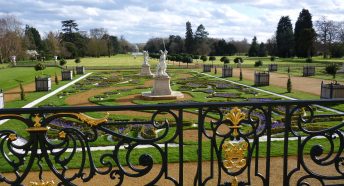 View of a parterre and formal gardens through ornate black railings.