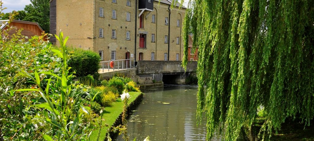 A large mill building next to a river.