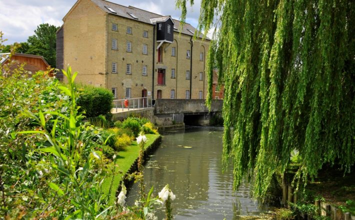 A large mill building next to a river.