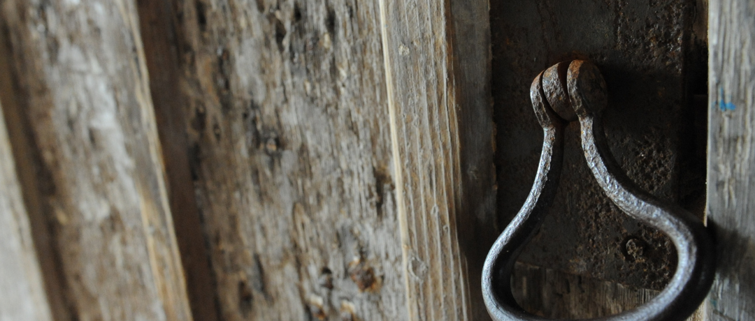 Black metal handle on wooden church door.