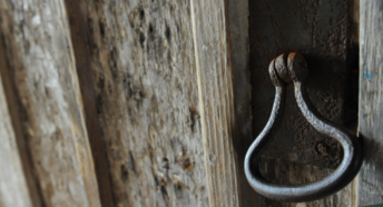 Black metal handle on wooden church door.