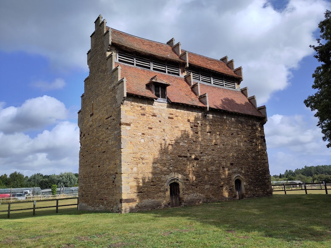 A large brick and tiled building in a field.