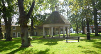 An open octagonal building on a village green.