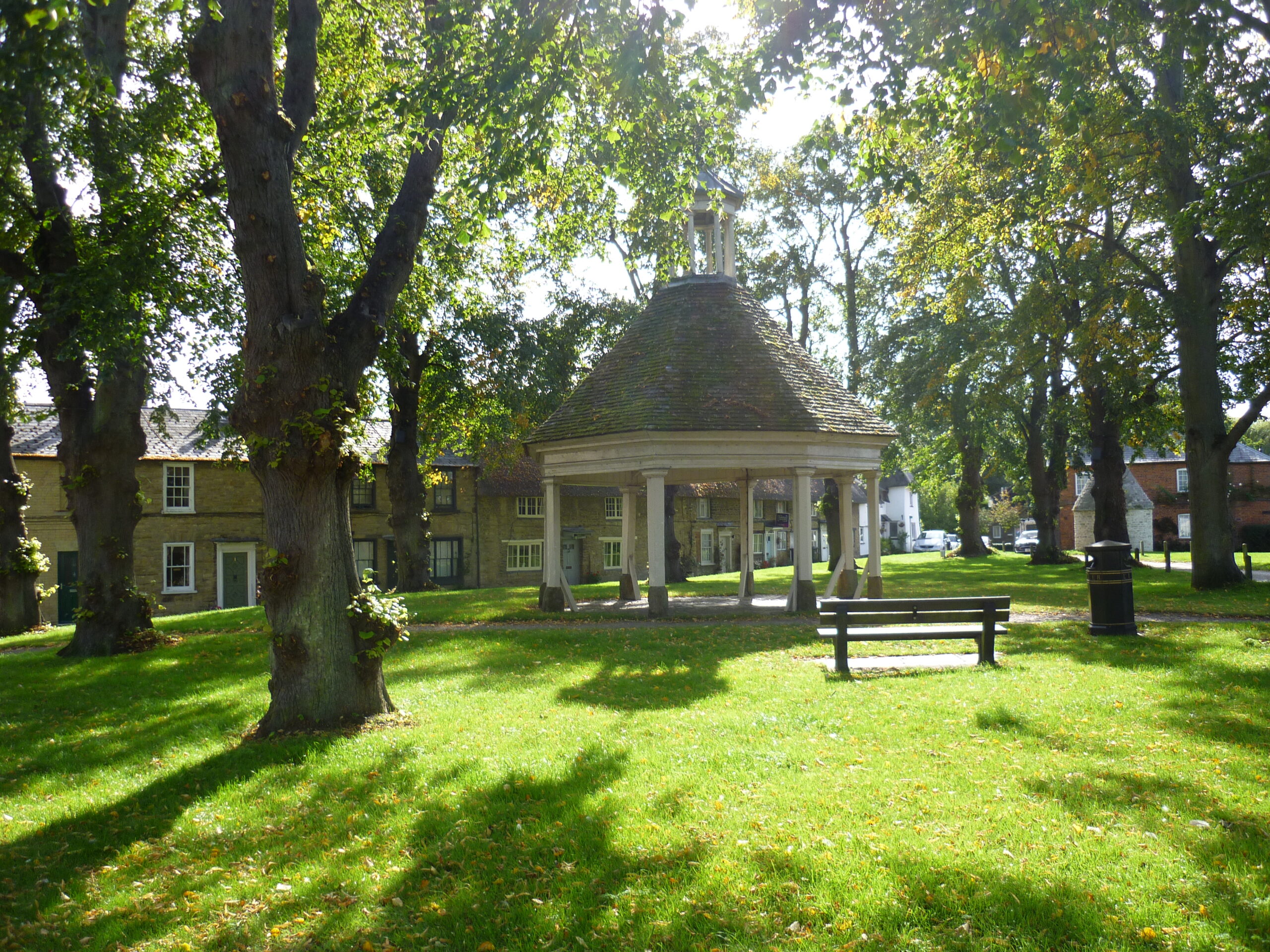 An open octagonal building on a village green.