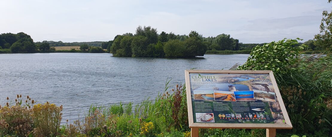A lake with visitor interpretation board in the foreground.