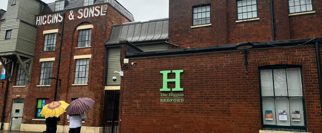 Two people with umbrellas standing outside Higgins Museum