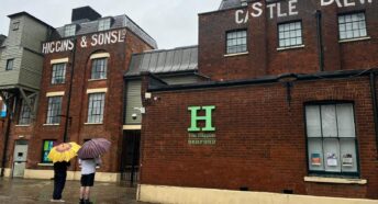 Two people with umbrellas standing outside Higgins Museum