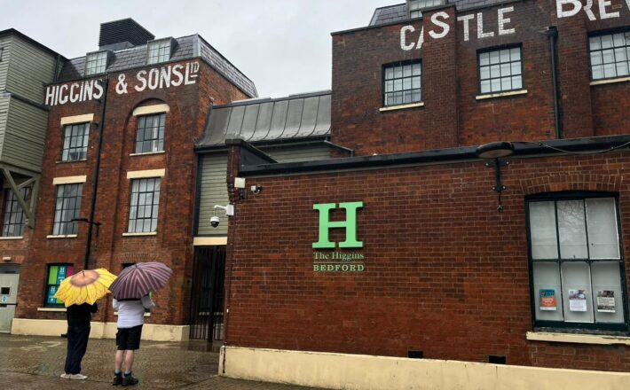 Two people with umbrellas standing outside Higgins Museum