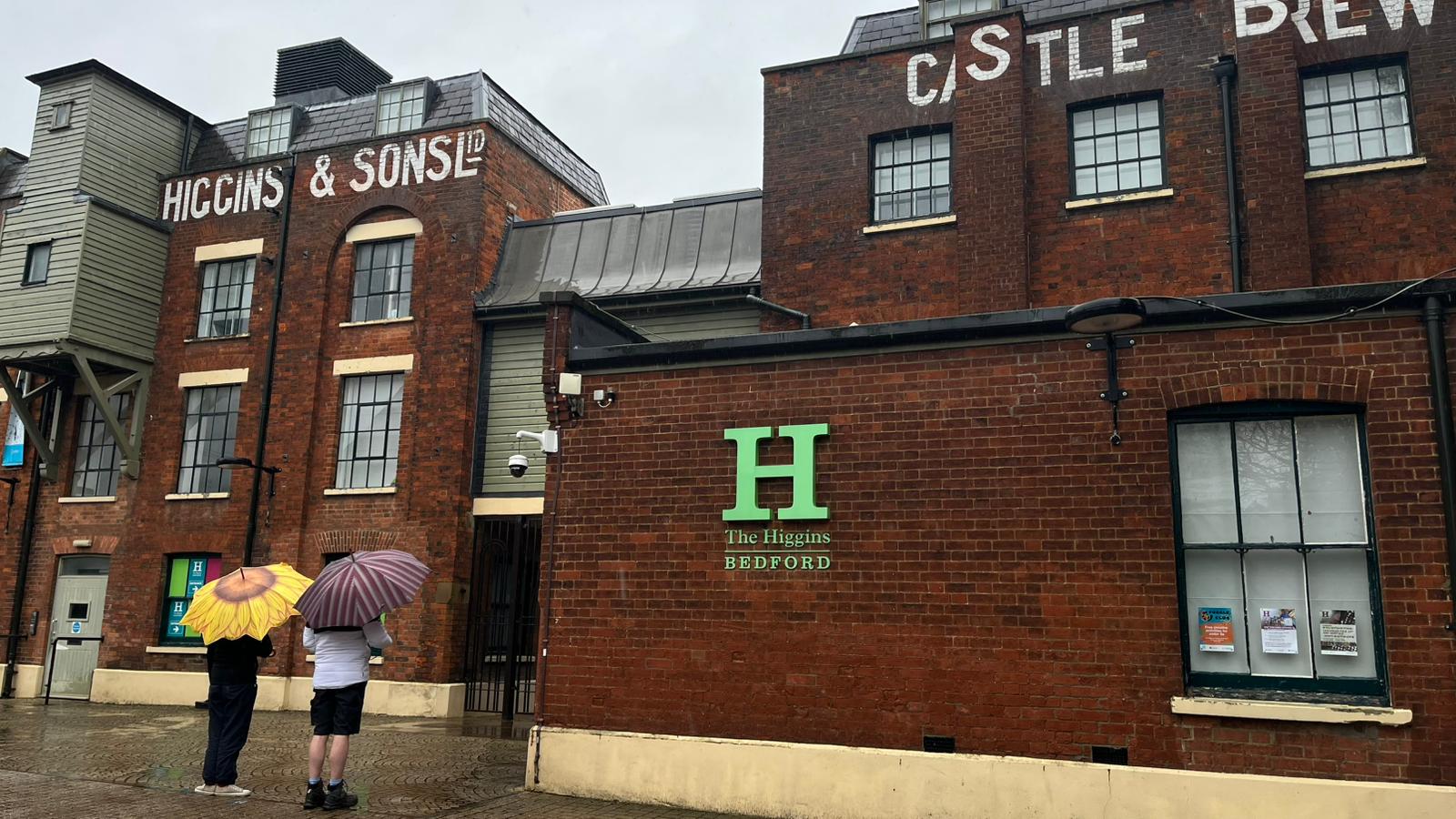 Two people with umbrellas standing outside Higgins Museum