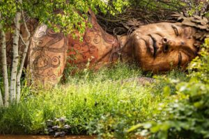 Mark Spencer Wood sculpture of Gia lying in a garden